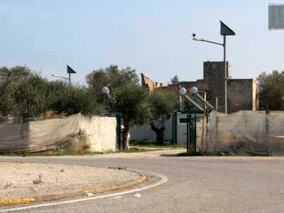 Quando il manto stradale comincia a scendere, imbocchiamo l'uscita a destra che immette in strada di Circonvallazione. Qui scarpiniamo per un centinaio di metri, costeggiando sulla sinistra un appezzamento di terreno recintato interamente da tendoni agricoli: � il campo rom "a cinque stelle" 